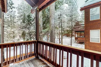 a balcony of a cabin with snow covered trees at Sierra Solstice in Truckee