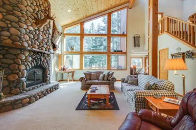 a living room with a large stone fireplace at Snowpeak Tahoe Donner Golf Course Views in Truckee