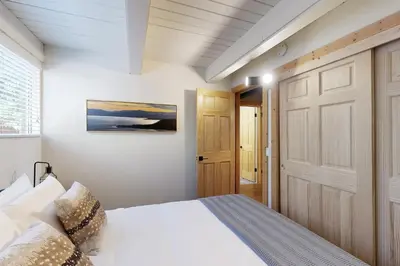 a bedroom with a white bed and a wooden door at Canterbury Kings Beach Treehouse in Kings Beach