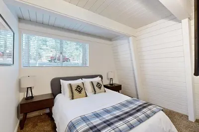 a white bedroom with a bed and two night stands at Canterbury Kings Beach Treehouse in Kings Beach