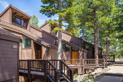 a home with a wrap around porch and trees at View Condo at Northstar in Truckee