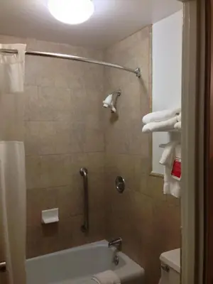 a bathroom with a tub and a shower with towels at Ramada by Wyndham Fresno North in Fresno