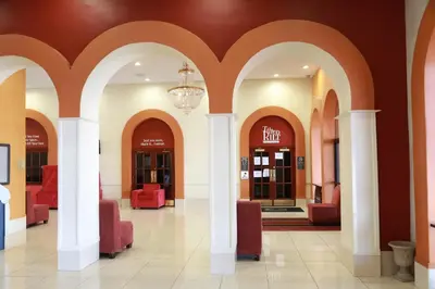 a lobby with red chairs and a chandelier at Ramada by Wyndham Fresno North in Fresno
