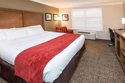 a hotel room with a large bed and a desk at Comfort Suites Fresno River Park in Fresno