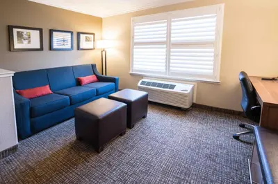 a living room with a blue couch and a window at Comfort Suites Fresno River Park in Fresno