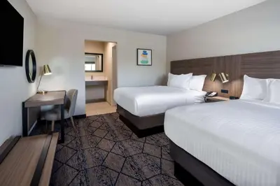 a hotel room with two beds and a desk at Ramada by Wyndham Modesto Yosemite Area in Modesto