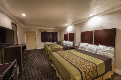 a hotel room with two beds and a flat screen tv at Edge Water Inn in Reedley