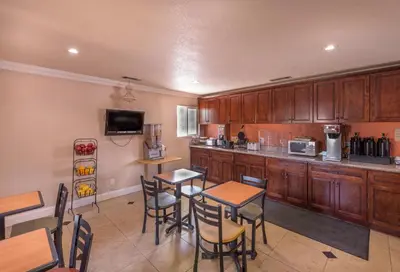 a kitchen with wooden cabinets and wooden tables and chairs at Edge Water Inn in Reedley