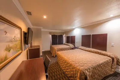 a hotel room with two beds and a television at Edge Water Inn in Reedley
