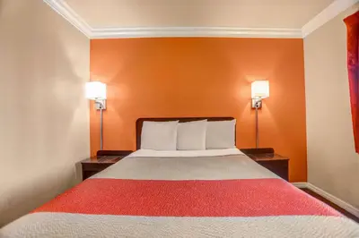 a bed in a room with orange walls and two lamps at Motel 6-Fresno, CA - Belmont Ave in Fresno