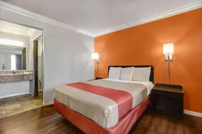 a hotel room with a bed with an orange wall at Motel 6-Fresno, CA - Belmont Ave in Fresno