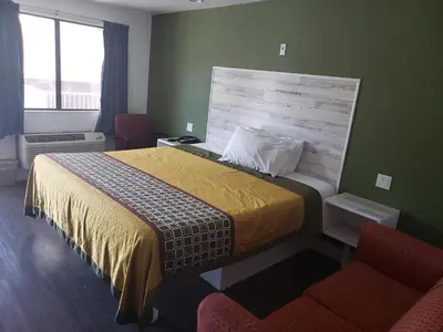 a hotel room with a bed and two chairs at University Inn Fresno in Fresno