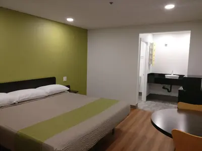 a bedroom with a bed and a table and a sink at Motel 6-Fresno, CA - Yosemite Hwy in Pinedale