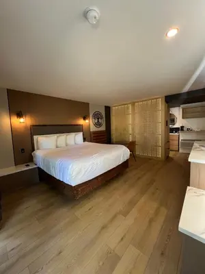 a bedroom with a large bed and a kitchen at Lamp Liter Inn Visalia, an Ascend Collection Hotel in Visalia