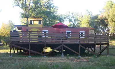 a red train car with an umbrella on a platform at Little Red Caboose in Oakhurst