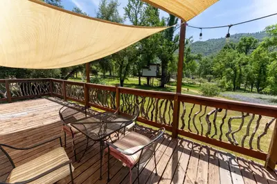 a deck with a table and chairs and a view at Little Red Caboose in Oakhurst