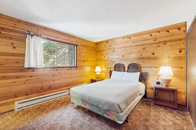 a bedroom with wooden walls and a bed and a window at Tahoma Getaway in Tahoma