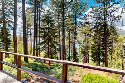 a wooden deck with a view of a forest at The Cherry Leaf Lodge & Retreat on Fallen Leaf Lake in Fallen Leaf