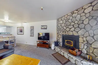 a living room with a stone wall with a fireplace at The Bridges 102 in Mammoth Lakes