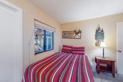 a bedroom with a bed with a striped bedspread and a window at The Bridges 102 in Mammoth Lakes