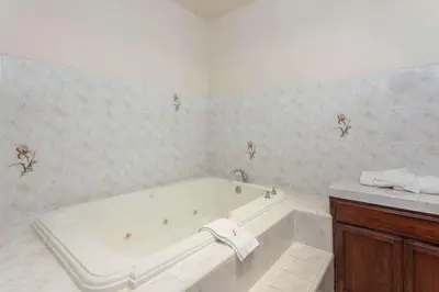 a white bathroom with a tub and a sink at Ramada by Wyndham Fresno Northwest in Fresno
