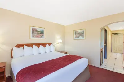 a hotel room with a large bed and a hallway at Ramada by Wyndham Fresno Northwest in Fresno