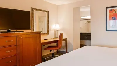 a hotel room with a bed and a desk with a television at Best Western Golden Key in Auburn