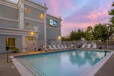 a swimming pool in front of a building with chairs at Best Western Luxury Inn in Tracy