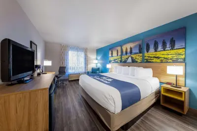 a hotel room with a bed and a flat screen tv at Days Inn by Wyndham Lathrop in Lathrop