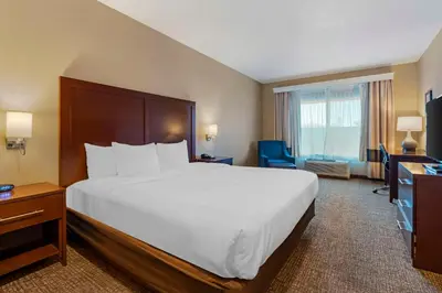 a hotel room with a large bed and a desk at Comfort Inn Lathrop Stockton Airport in Lathrop