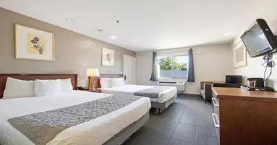 a hotel room with two beds and a flat screen tv at Budget Inn and Suites Stockton Yosemite in Stockton