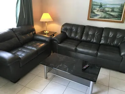 a living room with a leather couch and a coffee table at Garden Inn and Suites Fresno in Fresno