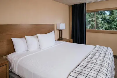 a bedroom with a large white bed with a window at Mammoth Mountain Inn in Mammoth Lakes