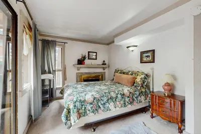 a bedroom with a bed and a table and a fireplace at Saddle Road Condo in Bijou Park