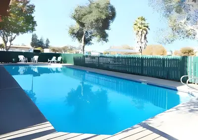 a swimming pool with a fence and blue water at Days Inn by Wyndham Gilroy in Gilroy
