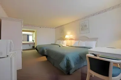 a hotel room with two beds and a desk at Days Inn by Wyndham Gilroy in Gilroy
