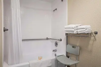 a bathroom with a shower and a toilet and towels at Days Inn by Wyndham Gilroy in Gilroy