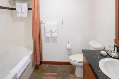 a bathroom with a toilet and a tub and a sink at The Village Lodge in Mammoth Lakes