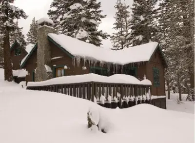 a house covered in snow in front at Tamarack Lodge in Mammoth Lakes