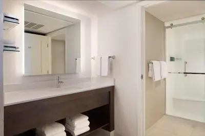 a bathroom with a sink and a mirror and a shower at Sonesta ES Suites Fresno in Fresno