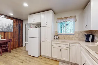 a kitchen with white cabinets and a white refrigerator at Peaceful Pines Retreat in Mevers