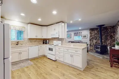 a kitchen with white cabinets and a stone wall at Peaceful Pines Retreat in Mevers