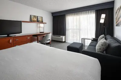 a hotel room with a bed and a couch and a television at Courtyard Sacramento Rancho Cordova in Rancho Cordova