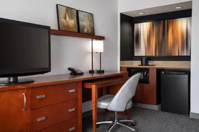 a hotel room with a desk with a television and a chair at Courtyard Sacramento Rancho Cordova in Rancho Cordova