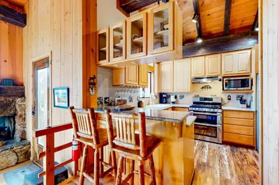 a kitchen with wooden cabinets and a bar with chairs at Commonwealth Retreat in Kings Beach