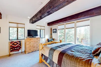a bedroom with a bed and a tv and windows at Commonwealth Retreat in Kings Beach