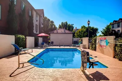 a swimming pool with two chairs next to a building at TownePlace Suites Fresno in Fresno