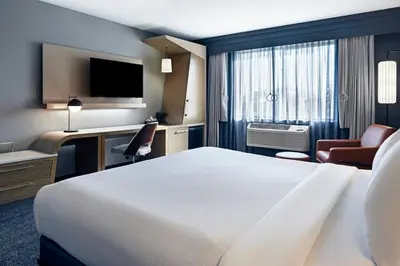 a hotel room with a bed and a desk and a tv at Courtyard by Marriott Sacramento Midtown in Sacramento