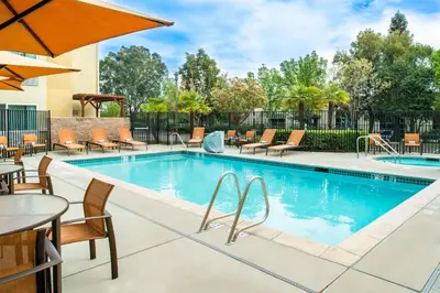 a pool with chairs and tables and a table with an umbrella at Courtyard by Marriott Sacramento Cal Expo in Sacramento