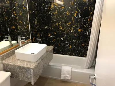 a bathroom with a sink and a bath tub with a window at Americas Best Value Inn Visalia in Visalia